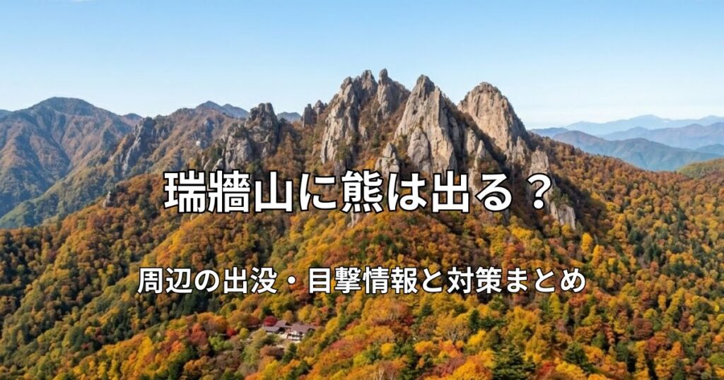 瑞牆山の特徴的な岩峰群と、麓に広がる鮮やかな紅葉の森を遠くから捉えた広角風景。青空の下に広がる秋の絶景。
